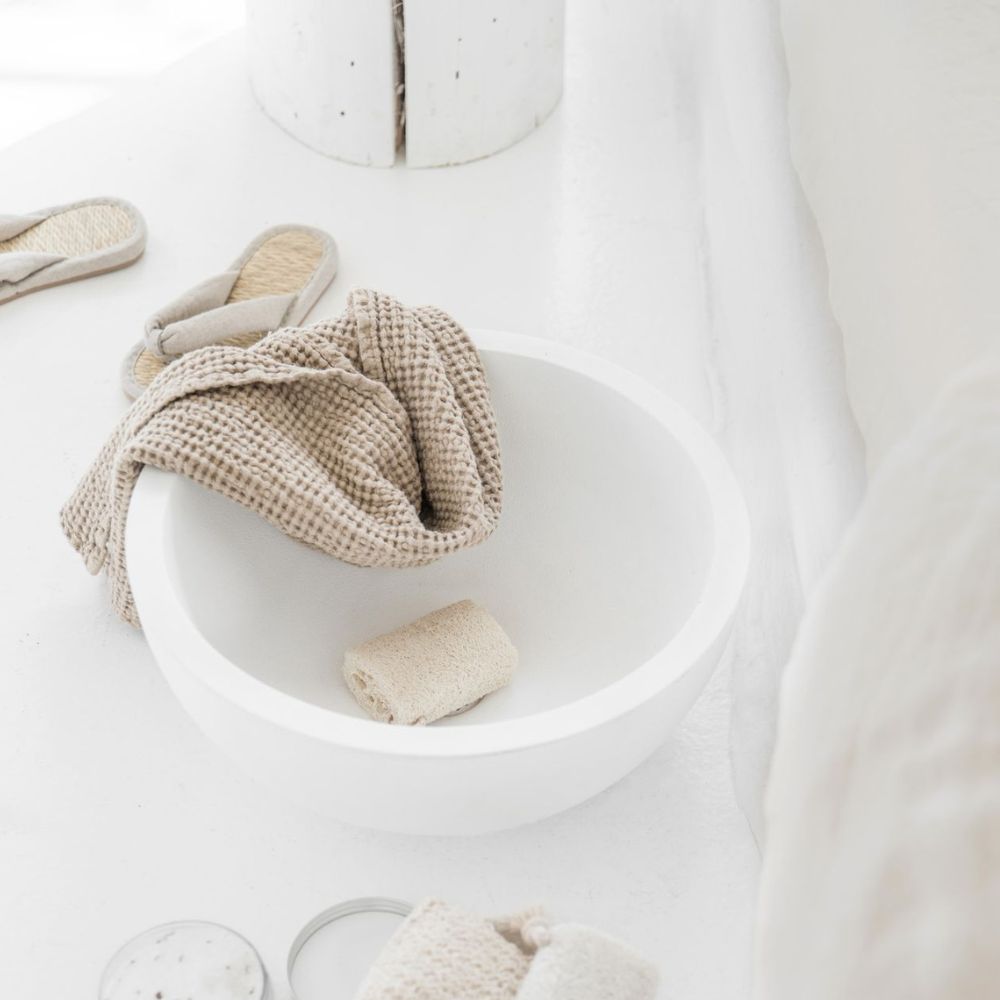 Naturlig ansiktshåndkle i vaffelvevd lin og bomull fra MagicLinen i beige, elegant plassert på et lyst bad med naturlige detaljer. Ideelt for daglig hudpleie og et sunt inneklima.