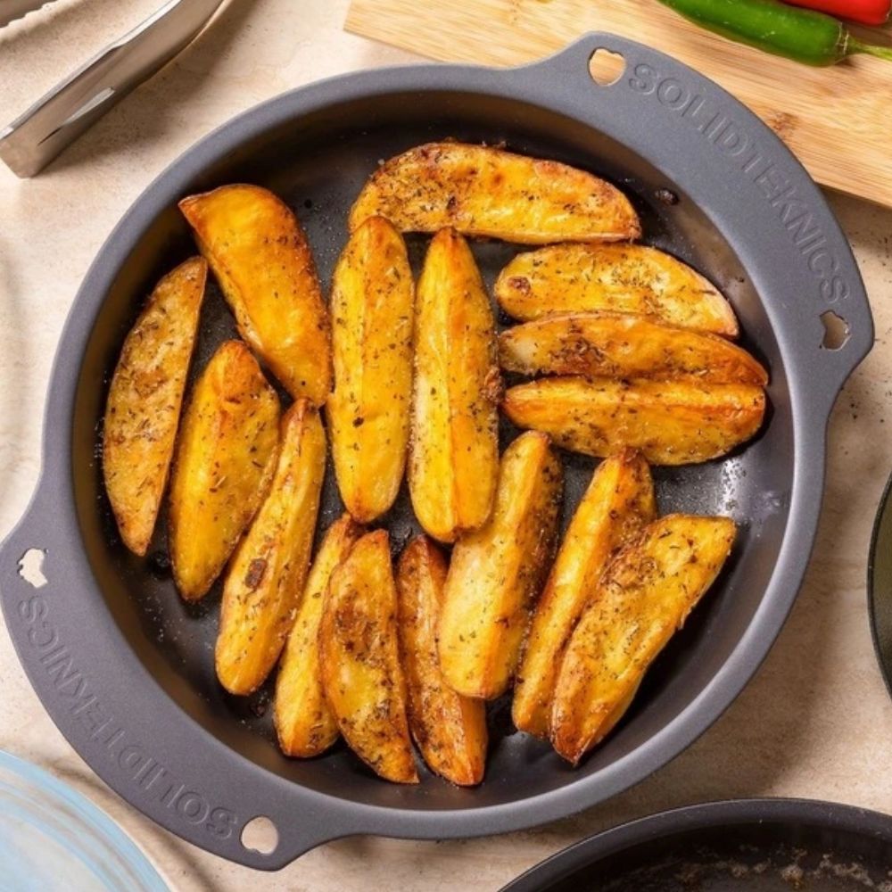 AUS-ION ovn-til-bord-panne fra Solidteknics fylt med sprøstekte poteter – laget i rent australsk jern uten belegg, med naturlig non-stick som forbedres med bruk.