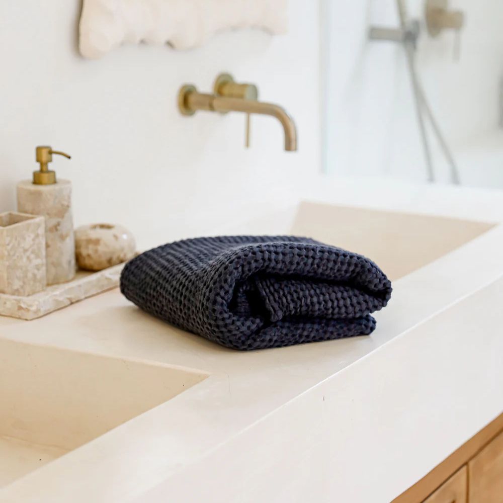 Mørkegrått badehåndkle i lin og bomull fra MagicLinen, vist på et lyst og rolig bad med naturlige detaljer som fremhever den luksuriøse kvaliteten.