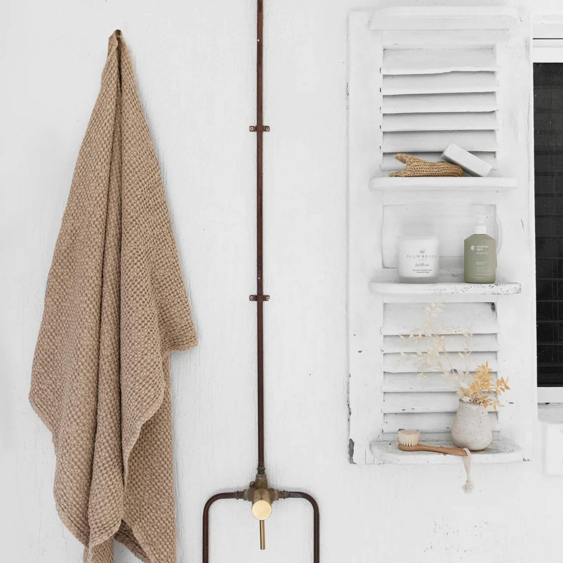 Beige badehåndkle i vaffelvevd lin plassert på et naturlig bad med lyse toner, treverk og en rolig, luksuriøs spa-følelse.