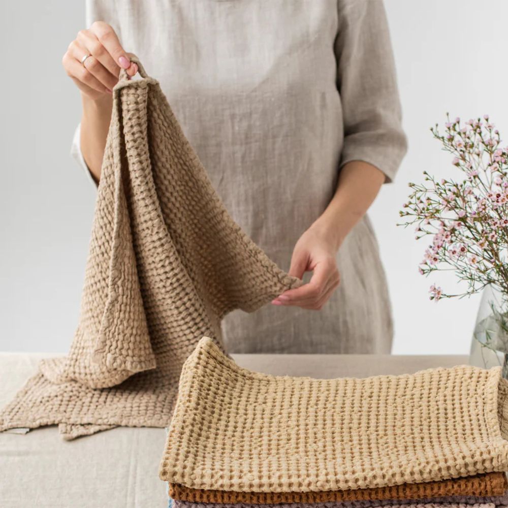 Dame holder MagicLinen kjøkkenhåndkle i lin og bomull i et lyst og sunt hjem, symboliserer naturlig og bærekraftig livsstil.
