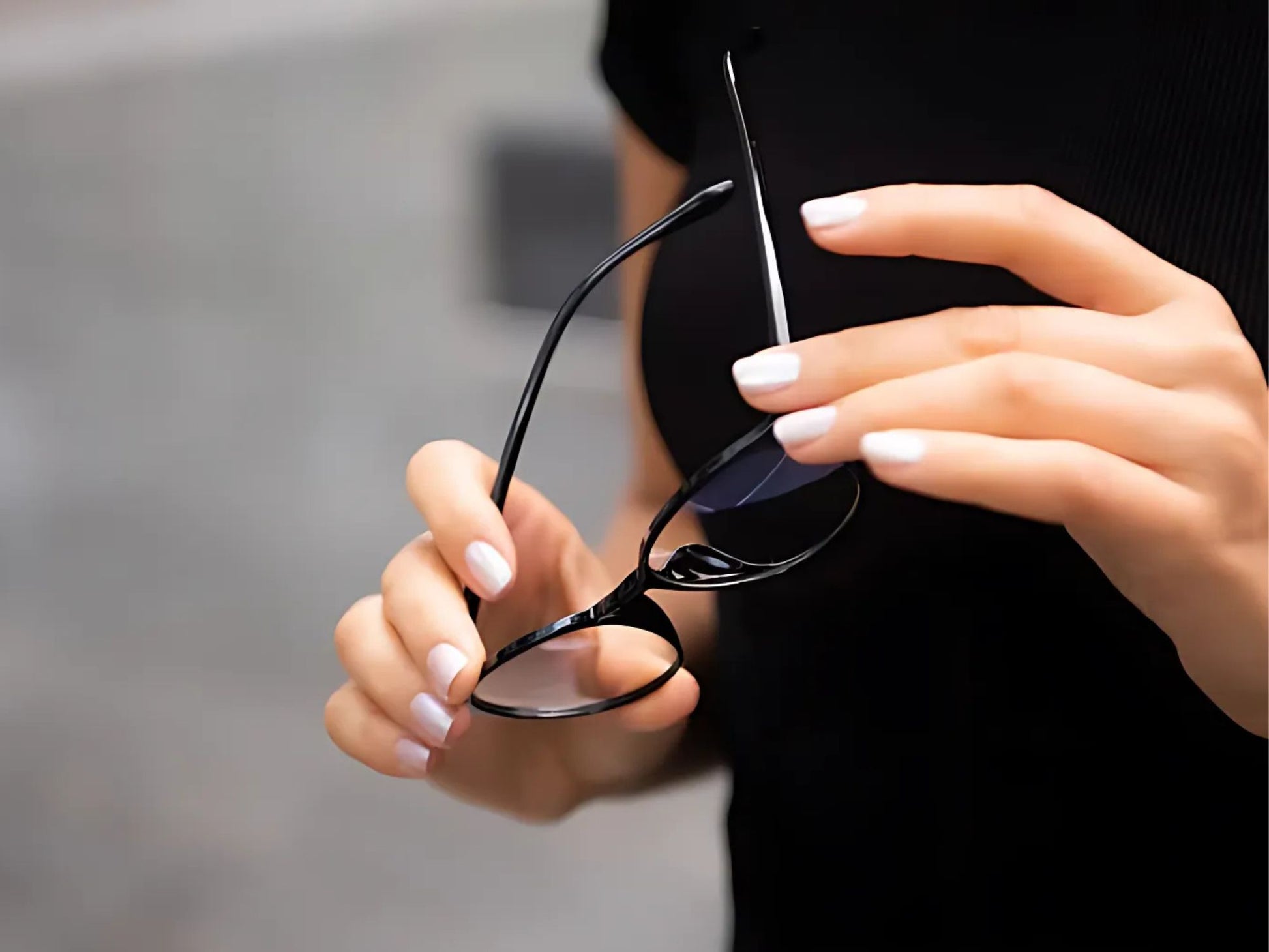 Damehånd som holder Ocushield Carson blålysbriller med sort innfatning og klare glass