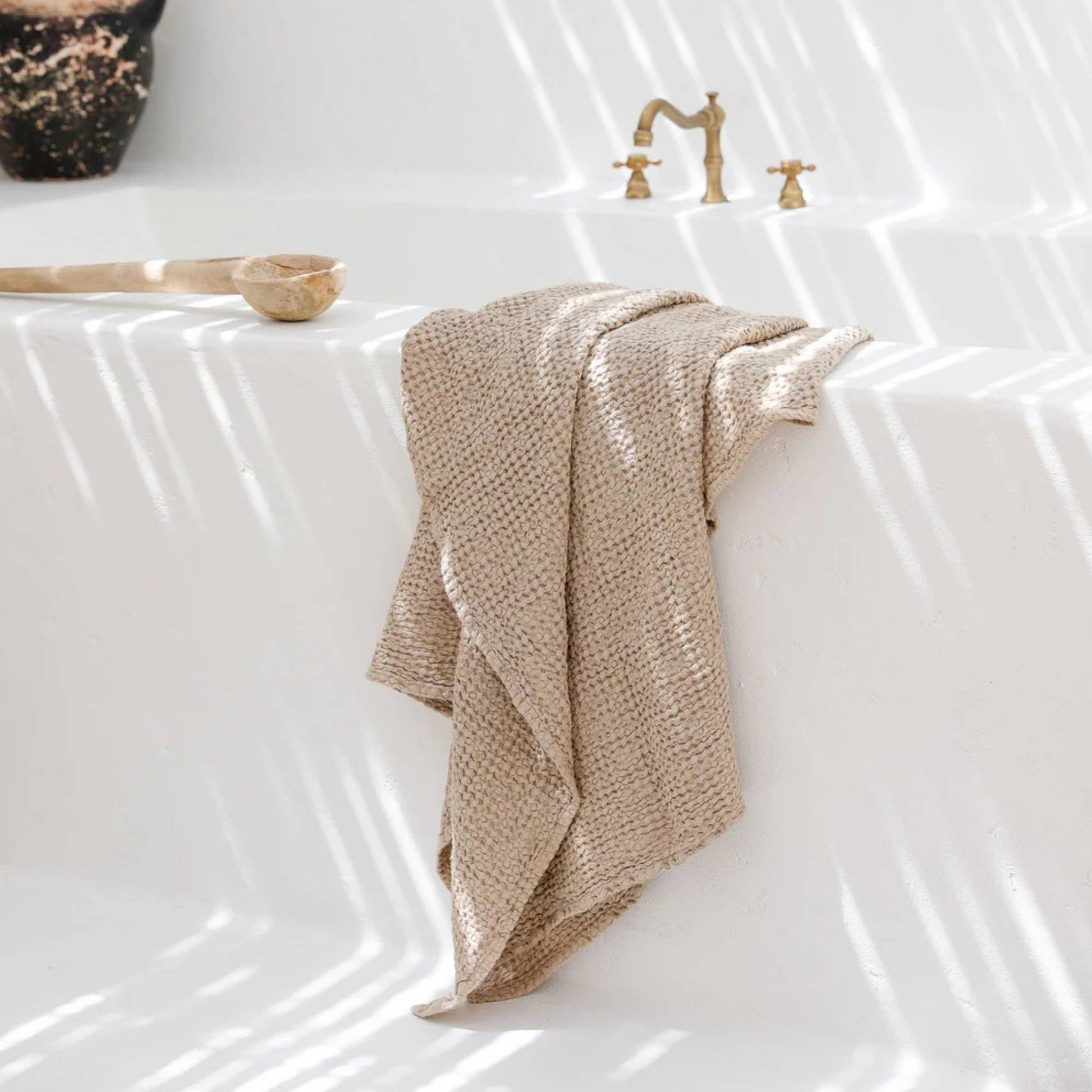 Luksuriøst beige linhåndkle i vaffelvevd struktur, elegant plassert på et moderne bad med naturlig lys.