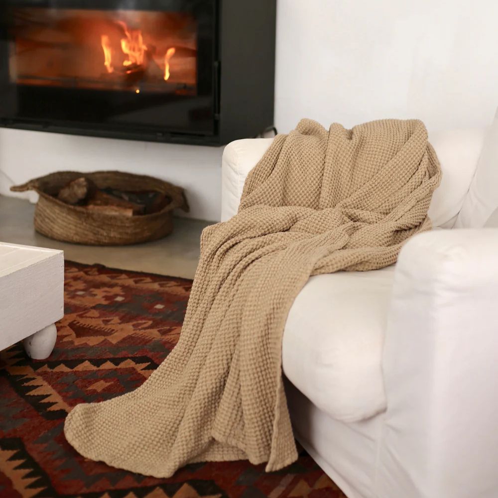 Beige vaffelvevd lin- og bomullspledd lagt over sofa, mykt og luksuriøst, ideelt for et sunt og bærekraftig hjem.