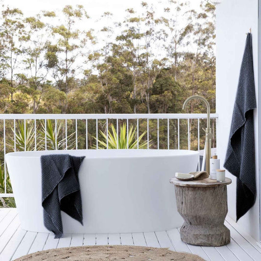 Mørkegrå badehåndkler i lin og bomull fra MagicLinen ved et utendørs bad, viser den naturlige teksturen og den rolige estetikken i materialene.