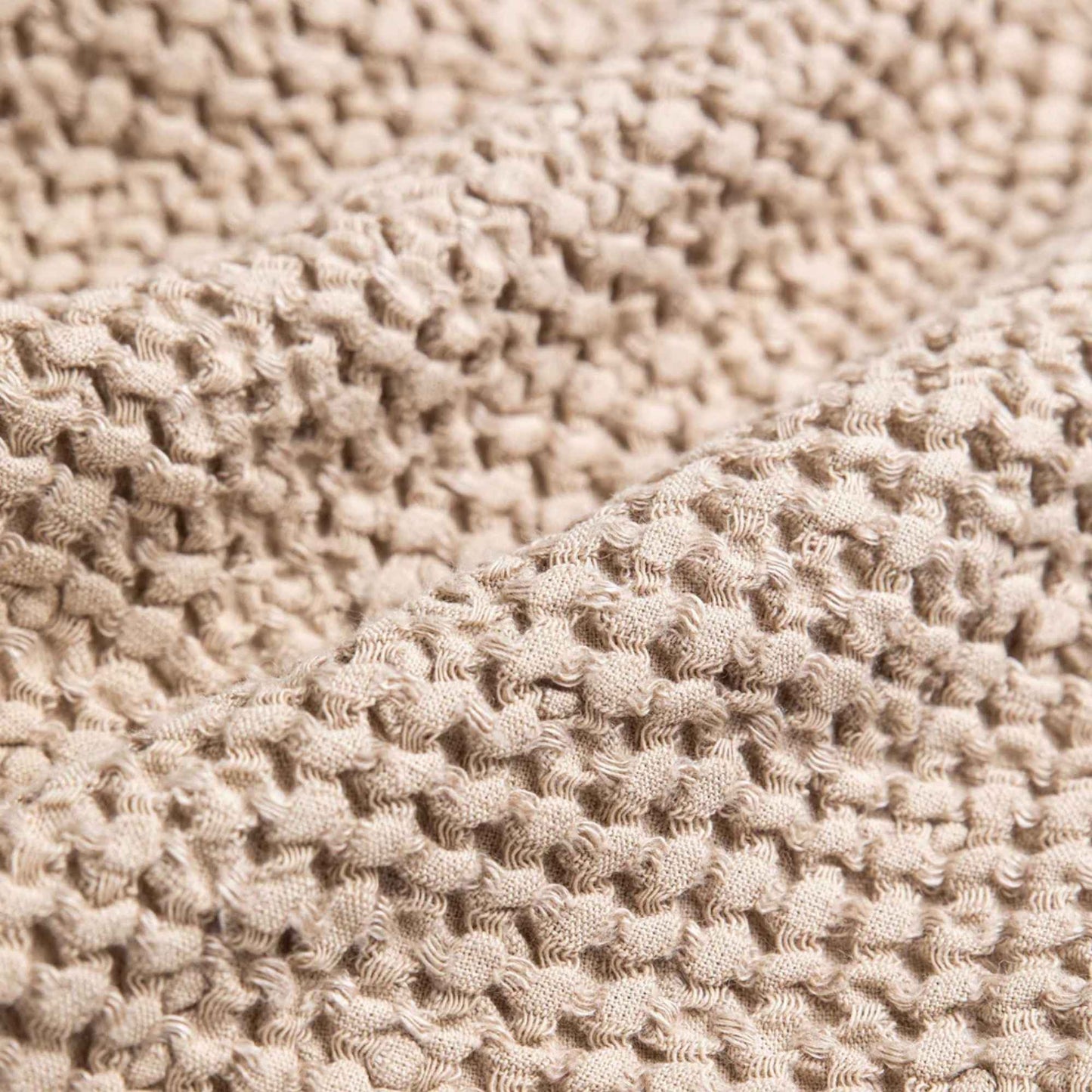 Nærbilde av beige håndkle i vaffelvevd lin som viser den luksuriøse, myke strukturen og naturlige fibrene.