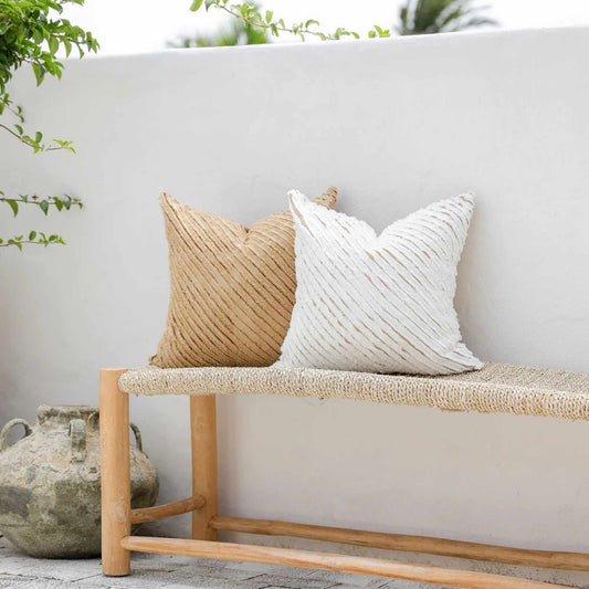 Stripete putetrekk i lin i naturlige farger plassert på en benk i et lyst uteområde