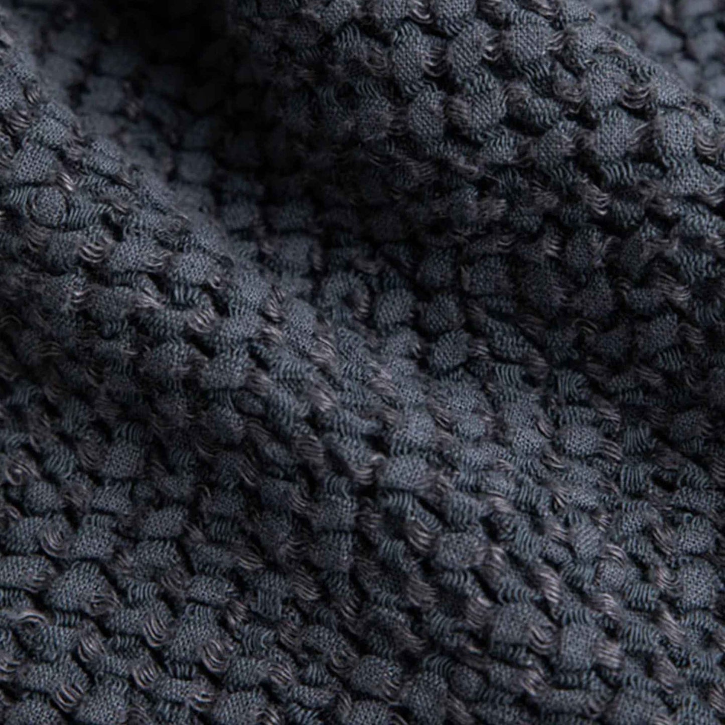 Nærbilde av vaffelstruktur i mørkegrått håndkle av lin og bomull fra MagicLinen, viser den luftige veven, naturlige teksturen og håndverkskvaliteten.