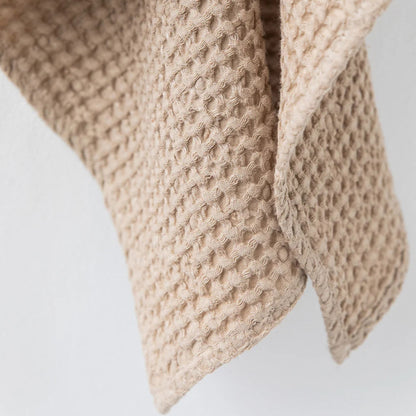 Detaljbilde av vaffelstruktur i beige ansiktshåndkle laget av lin og bomull fra MagicLinen. Viser naturlig tekstur som gir mykhet, rask tørking og skånsom peeling. Ideelt for sensitiv hud og et sunt hjem.