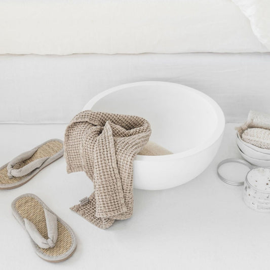 Beige ansiktshåndkle i vaffelvevd lin og bomull fra MagicLinen, pent plassert på en baderomsvask. Naturlig og mykt tekstil som er skånsomt mot huden og passer inn i et sunt hjem.