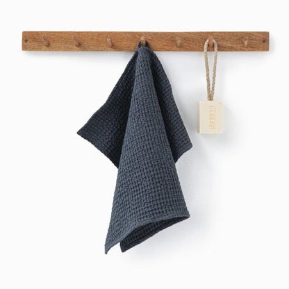 Mørkegrått ansiktshåndkle i lin og bomull fra Magiclinen, hengt på knagg for å vise naturlig tekstur og rask tørk.
