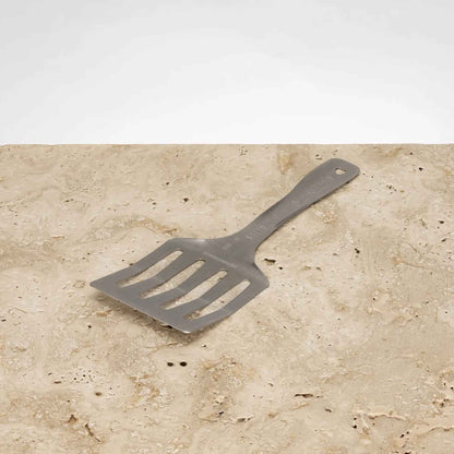 Flexi Flippa stekespade i rustfritt stål fra Solidteknics på steinbenk. Plastfri stekespade laget av ett solid stykke rustfritt fjærstål.