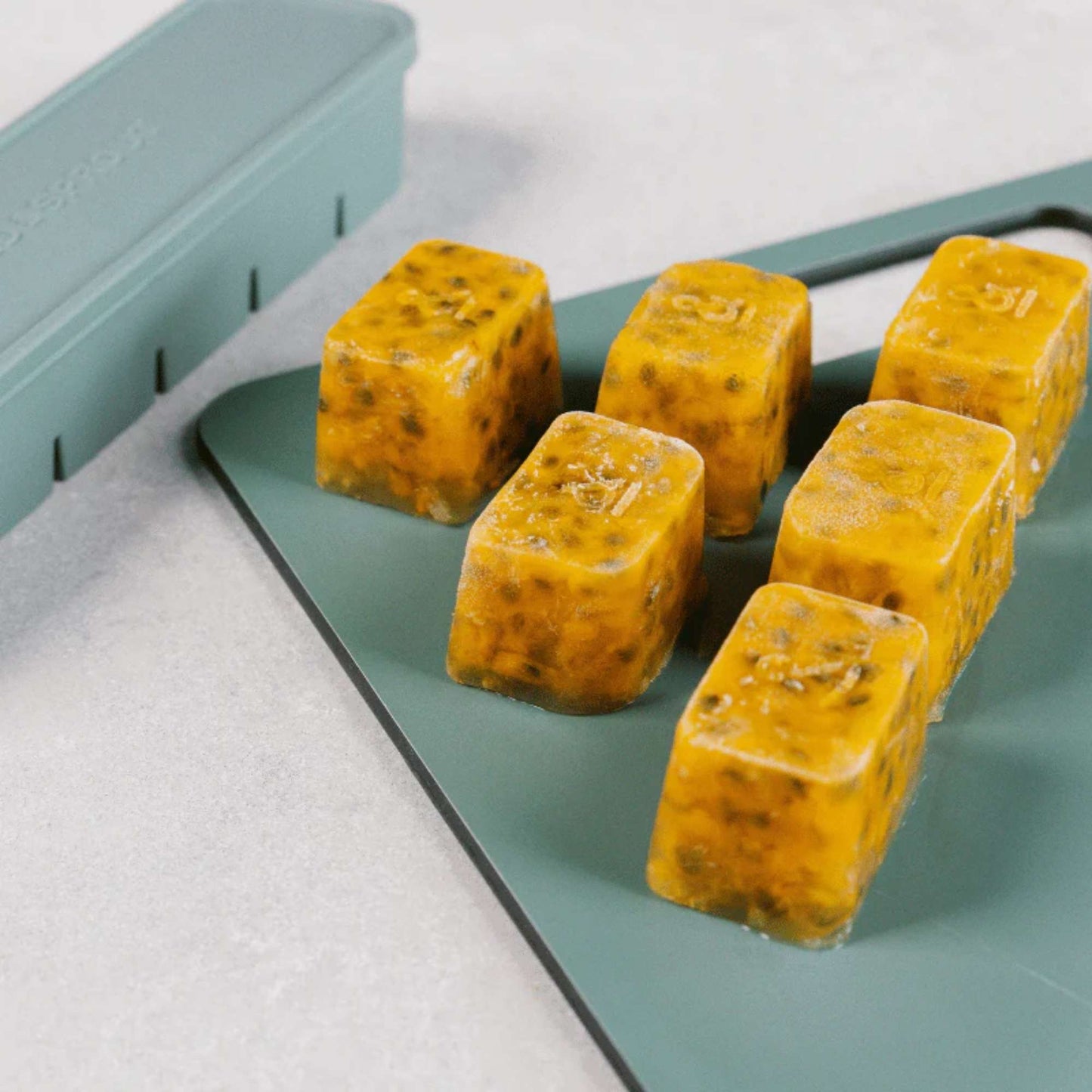 Frosne porsjonsklosser tatt ut av en LFGB-sertifisert silikonfryseform i fargen Eucalyptus fra Seed & Sprout. Perfekt for babymat, kraft, sauser og smoothie-porsjoner.