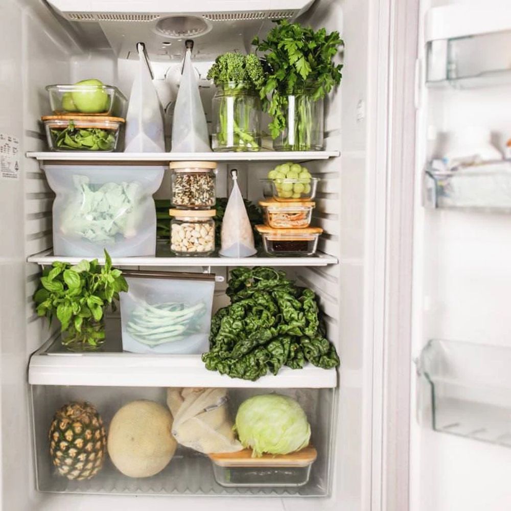 Gjenbrukbare silikonposer fra Seed & Sprout fylt med grønnsaker og frukt i et organisert, sunt kjøleskap, et bærekraftig valg som reduserer plast og holder maten frisk lenger.
