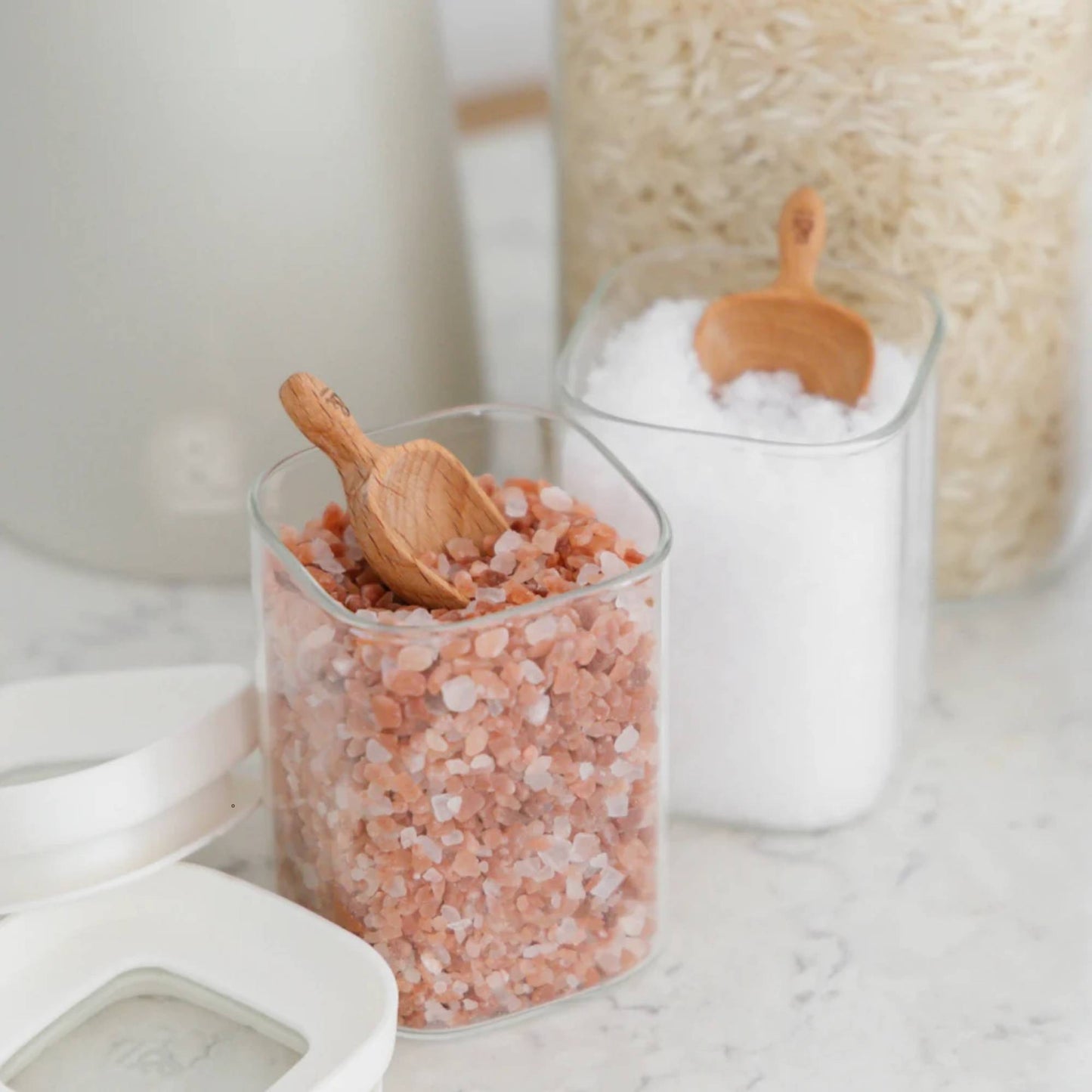Glassbeholder med glasslokk fylt med salt og ris brukt til plastfri oppbevaring av ingredienser på kjøkkenet.