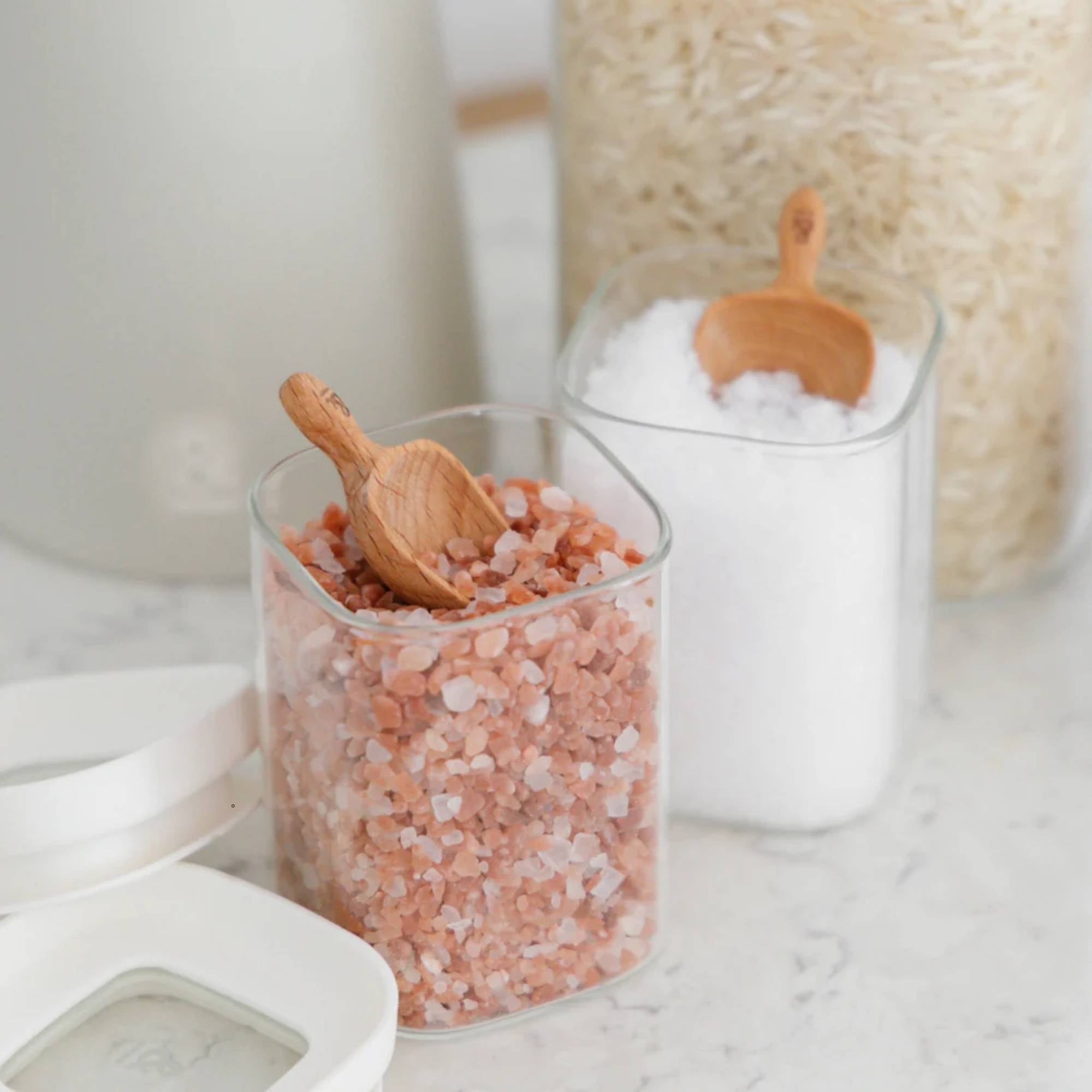 Glassbeholder med glasslokk fylt med salt og ris brukt til plastfri oppbevaring av ingredienser på kjøkkenet.