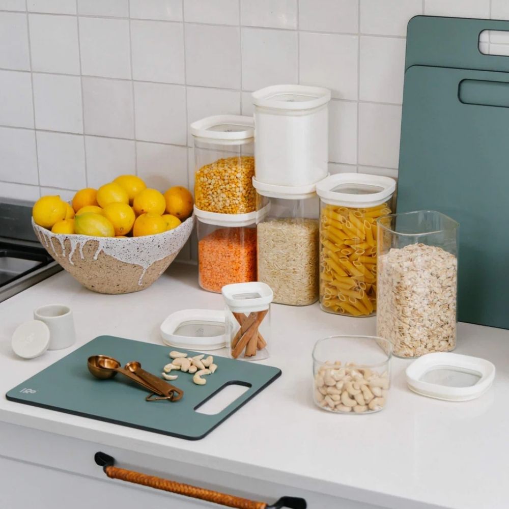 Glassbeholdere i borosilikatglass med glasslokk fylt med pasta, ris og linser brukt til plastfri pantry-oppbevaring på kjøkkenet.
