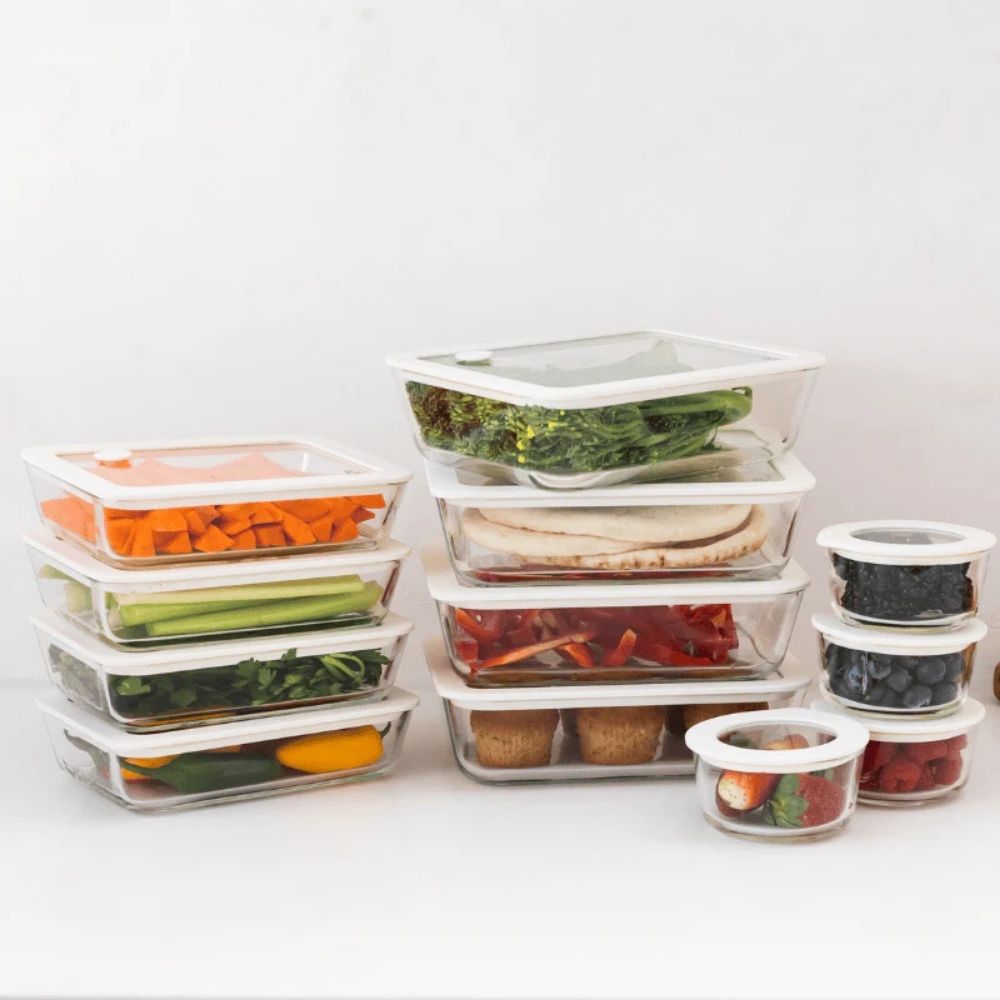 Firkantede og runde glassbeholdere med glasslokk fylt med mat, stablet på kjøkkenbenk. Plastfri matoppbevaring i borosilikatglass.
