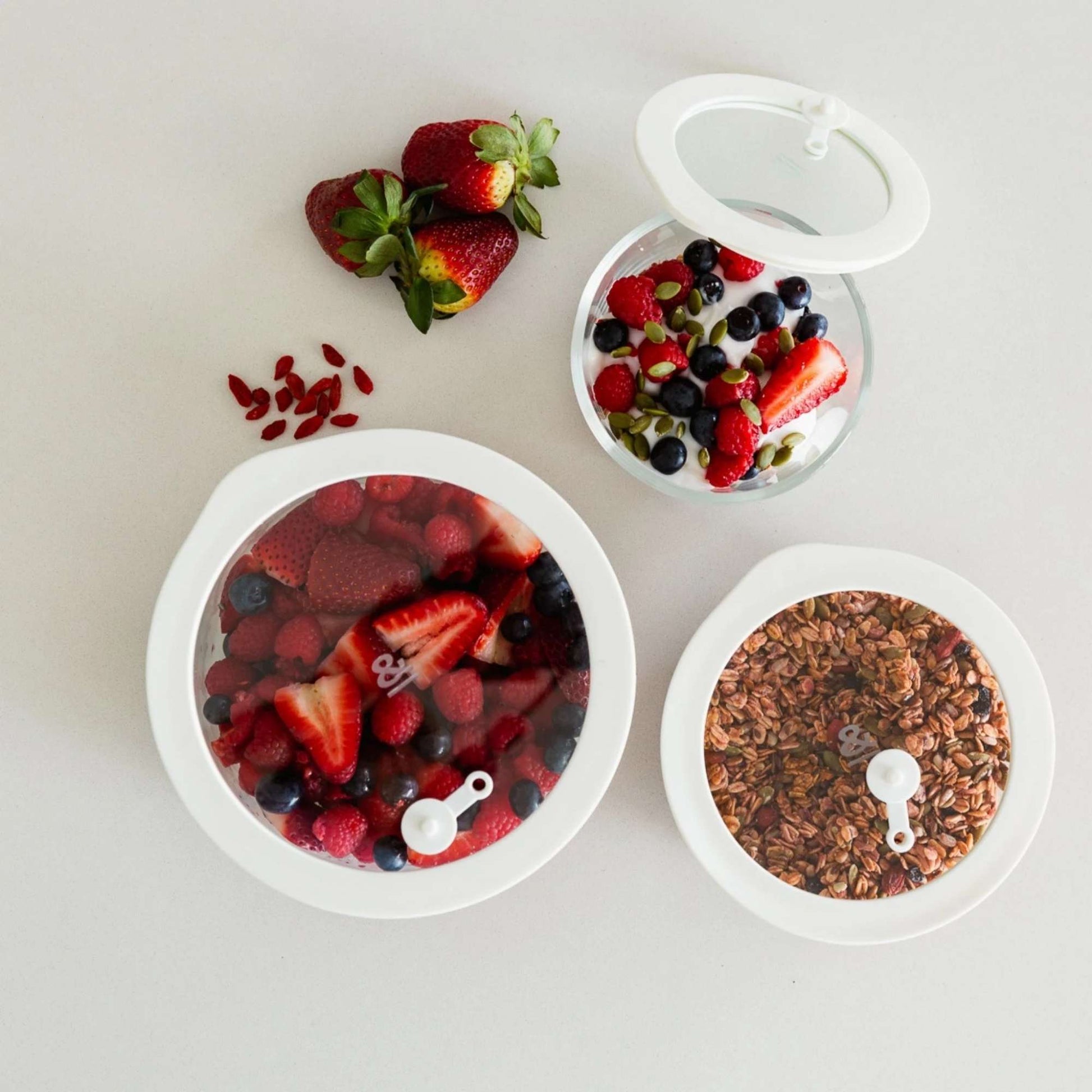 Runde glassbeholdere med glasslokk brukt til oppbevaring av bær, frukt og granola på kjøkkenbenk
