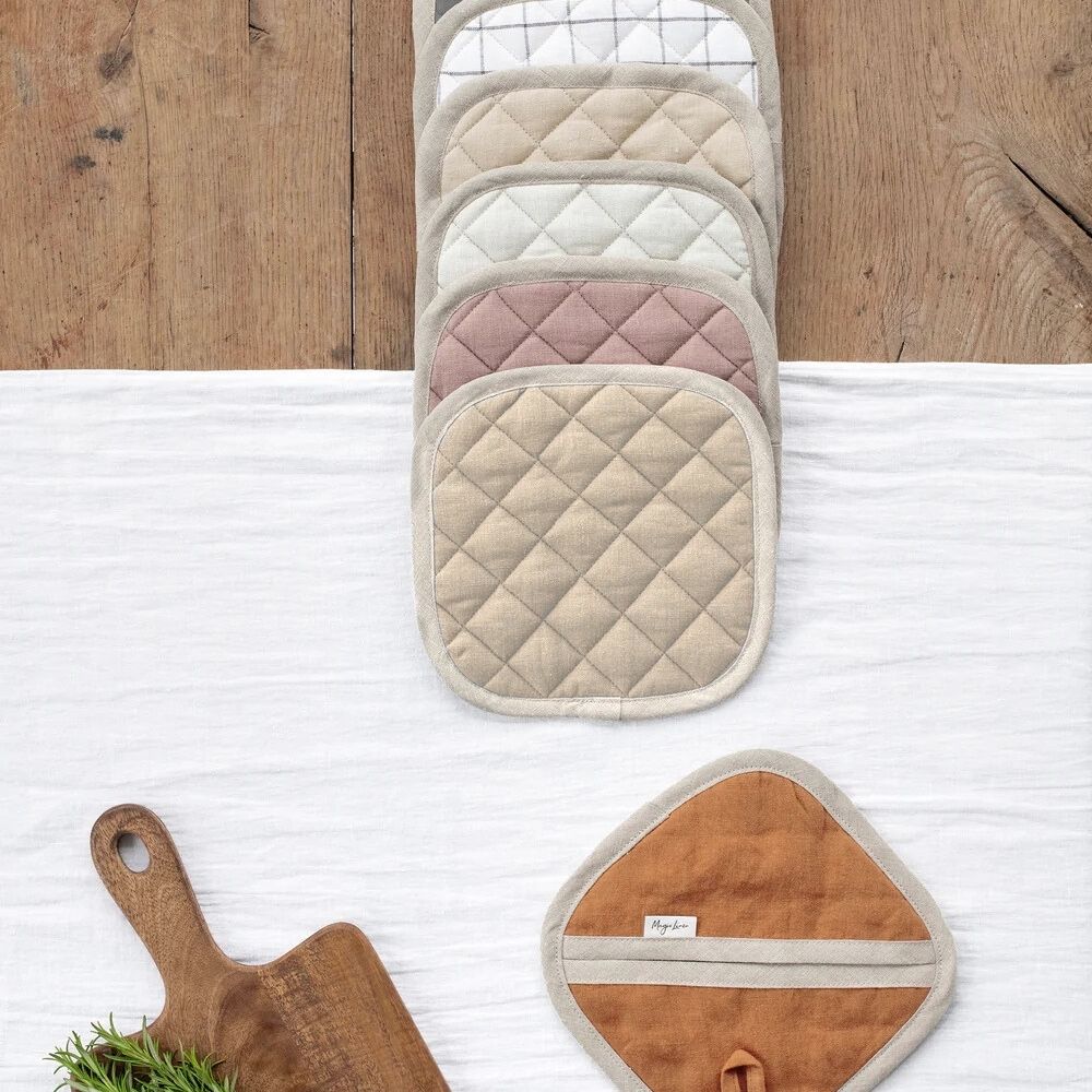 Flere grytekluter i 100 % lin i ulike farger, vist samlet på kjøkkenbord for å fremheve design og tekstur.