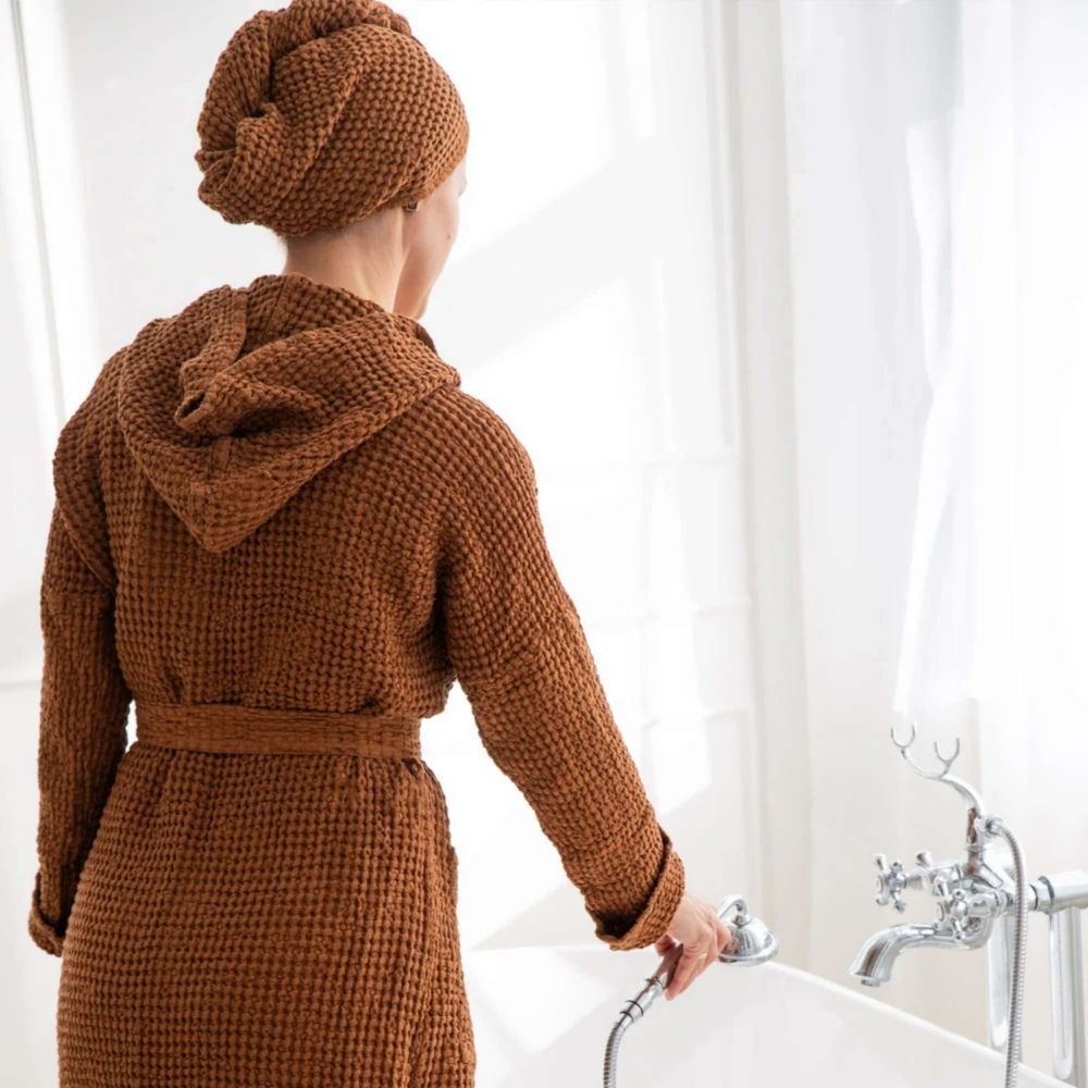 Kvinne med vaffelvevd hårhåndkle turban i lin og bomull i fargen cinnamon, brukt etter dusj for skånsom og hurtigtørkende hårtørk.