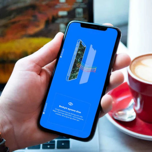 Hånd som holder iPhone med Ocushield skjermbeskytter – teksten på skjermen lyder: "Beskytt øynene dine: unngå belastninger og ubehag som ofte følger med mye skjermtid