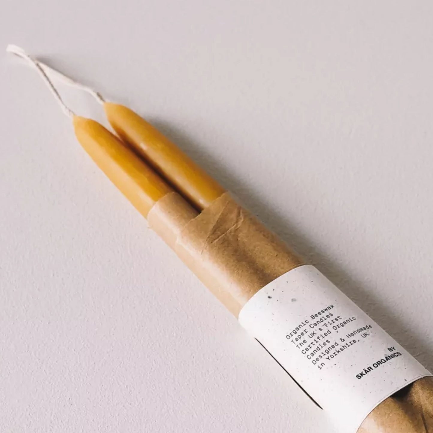 Økologiske bivokskronelys pakket i plastfri emballasje med etikett fra Skär Organics