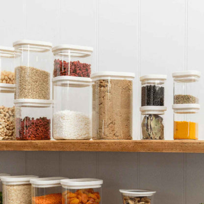 Krydderglass og glassbeholdere med glasslokk fylt med krydder og tørrvarer organisert på kjøkkenhylle.