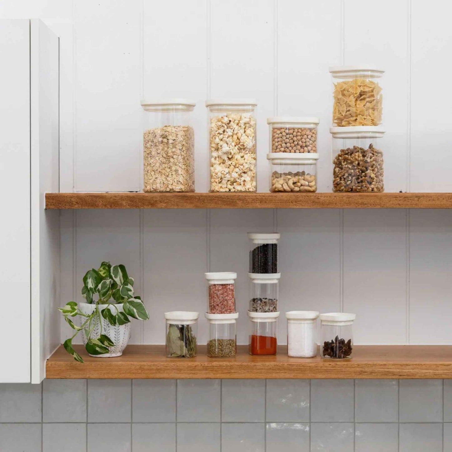 Krydderglass og glassbeholdere med glasslokk organisert på kjøkkenhyller for plastfri oppbevaring av krydder og tørrvarer.