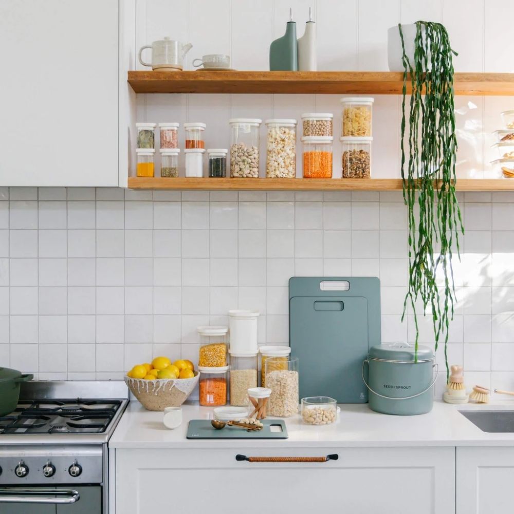 Krydderglass og glassbeholdere med glasslokk organisert på kjøkkenhylle for plastfri oppbevaring av krydder og tørrvarer.