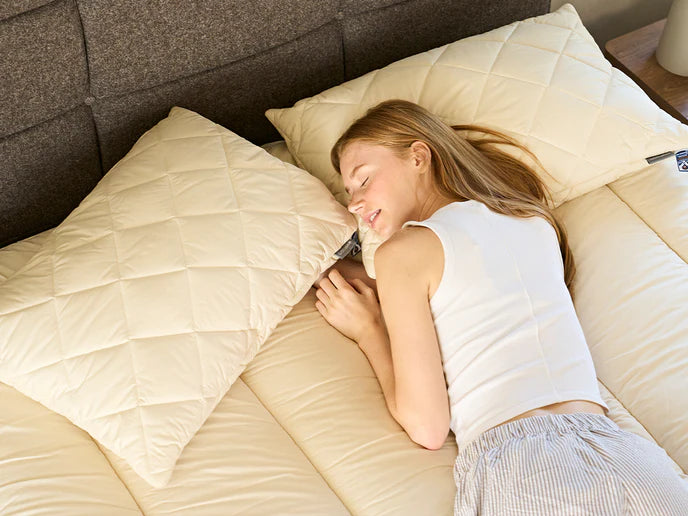 Kvinne sover godt på overmadrass i naturmaterialer fra Woolroom