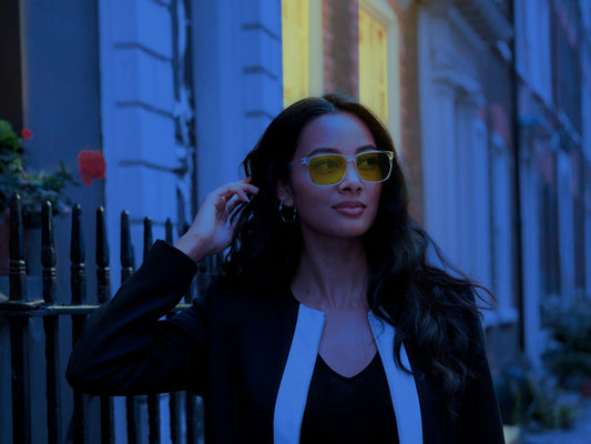 Kvinne utendørs om kvelden med Ocushield Parker blålysbriller med klar innfatning og oransje glass for skjermbruk og bedre søvn