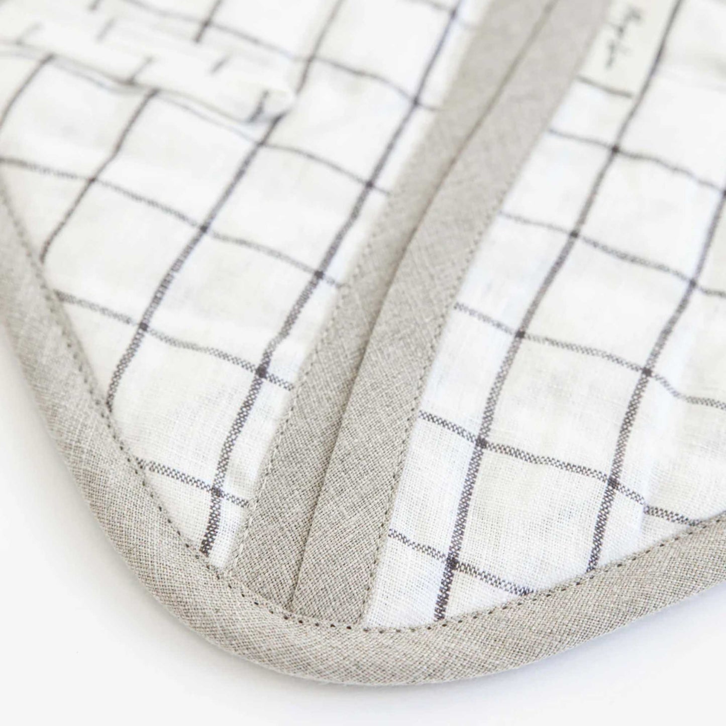 Detaljbilde av gryteklut i lin fra MagicLinen med koksgrått rutemønster og tekstilkant.