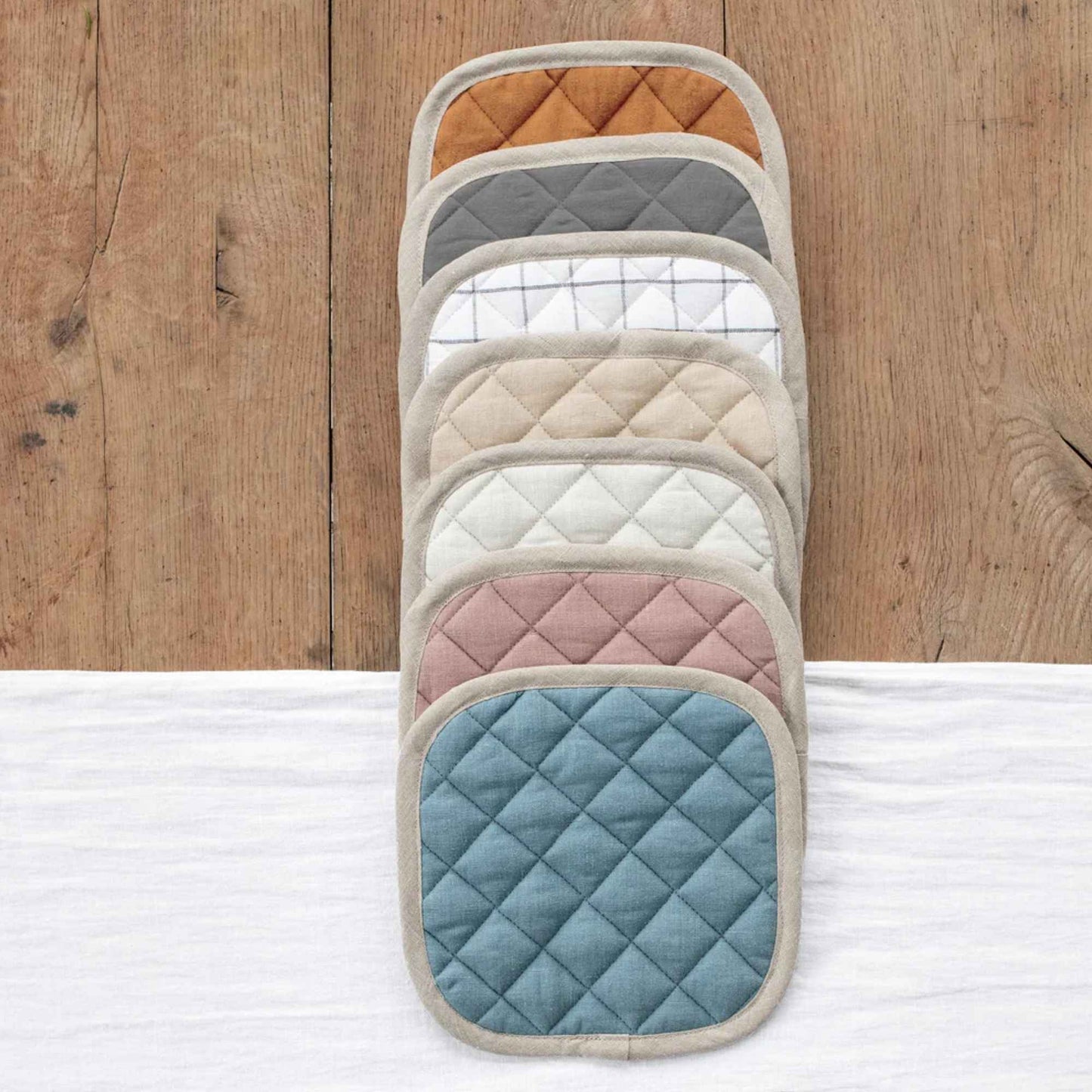 Flere grytekluter i lin fra MagicLinen vist i ulike farger som blå, rosa, natur, hvit, grå og kanel.