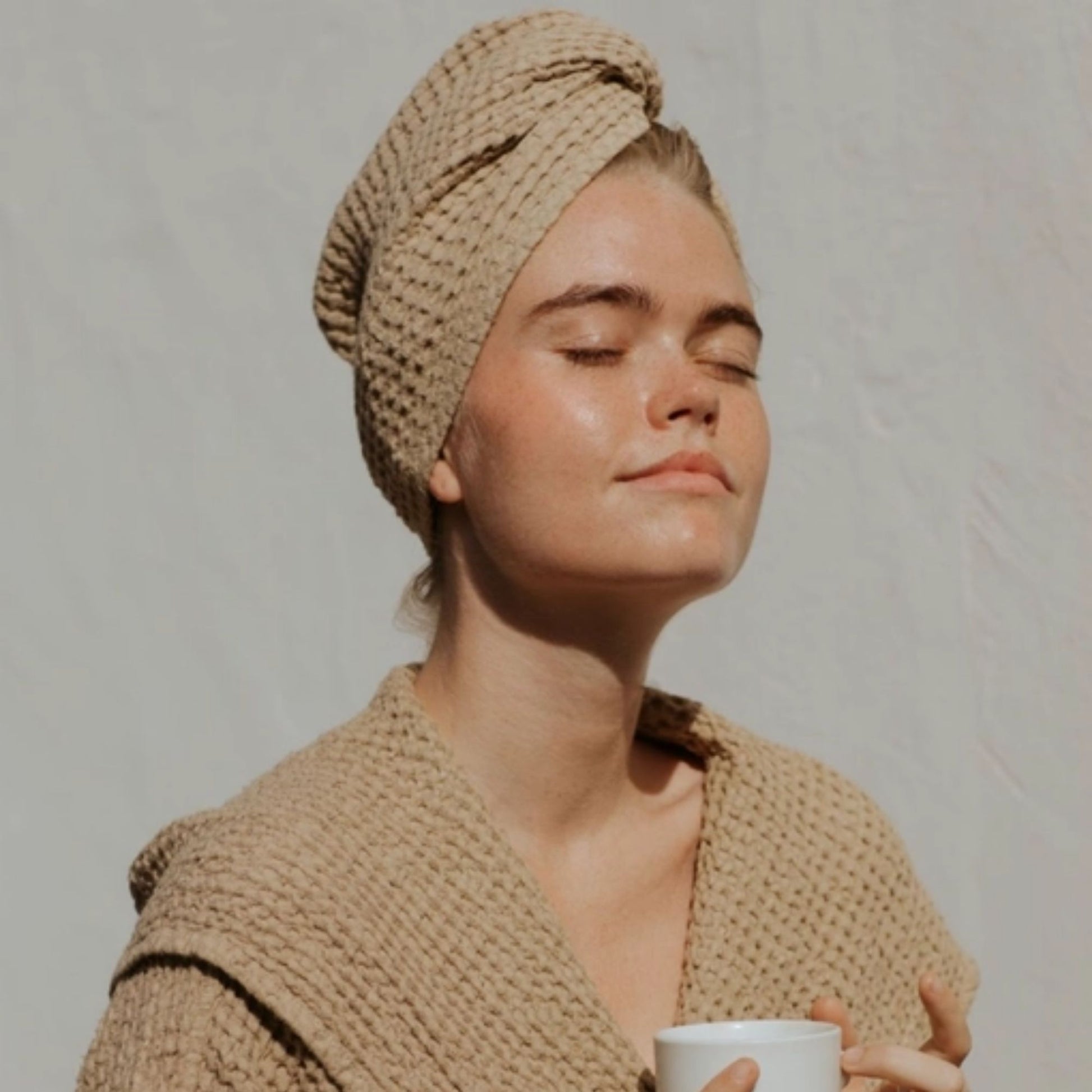 Kvinne med MagicLinen beige lin hårturban i vaffelstruktur, naturlig og plastfritt alternativ for skånsom tørking av hår.