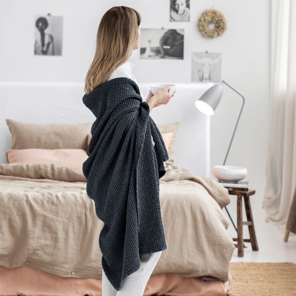 Kvinne pakket inn i mørkegrå MagicLinen pledd laget av lin og bomull, koselig og komfortabelt
