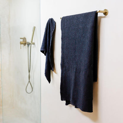 Badehåndkle og håndhåndkle i mørkegrå lin med vaffelstruktur hengt opp på badet