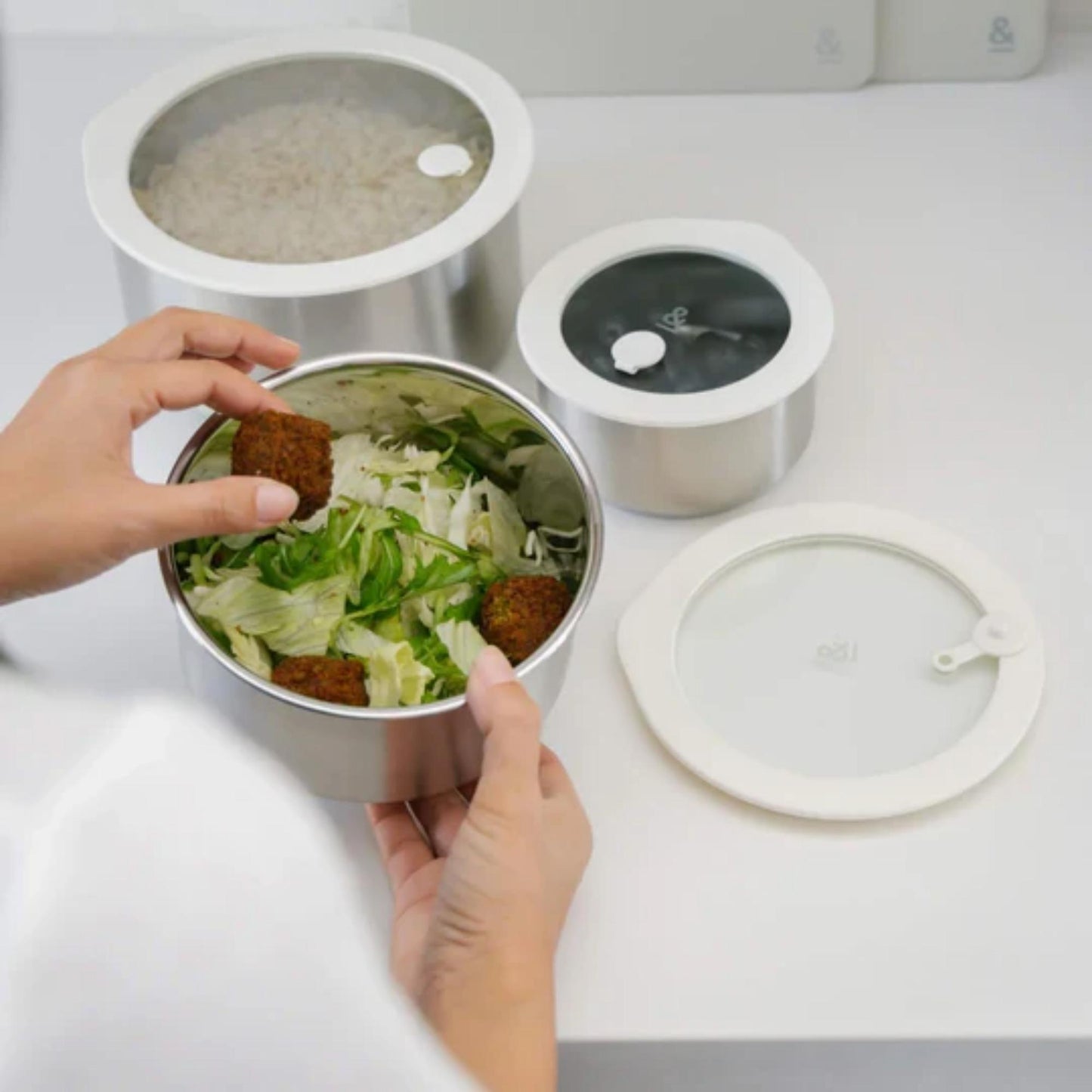 Matbokser i rustfritt stål med glasslokk brukt til oppbevaring av salat og rester. Et varig alternativ til plastbokser for matoppbevaring i kjøleskap og fryser.