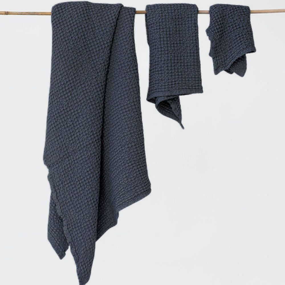 Håndklesett i mørkegrå lin og bomull fra MagicLinen. Badehåndkle, håndhåndkle og ansiktshåndkle henger samlet på en snor. Ideelt for et sunt og bærekraftig hjem.