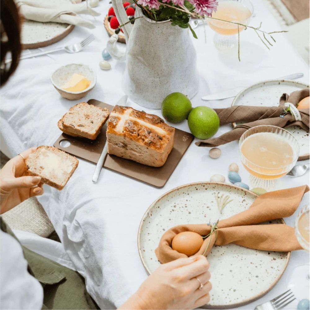 Mini Wood Fibre skjærefjøl i fargen Nutmeg brukt til å skjære og servere brød på et dekket frokostbord.