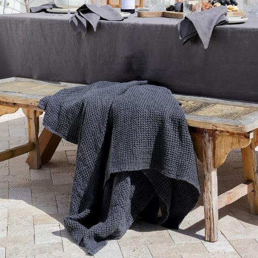  Mørkegrått waffle pledd i lin og bomull brukt utendørs på en sommerdag, lett og pustende for komfort i varmt vær.