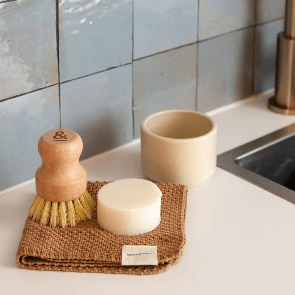 Myk gryteskrubb i plantefiber fra Seed & Sprout brukes til oppvask på kjøkkenbenk. Skånsom, plastfri og komposterbar skrubb for daglig rengjøring uten kjemikalier.