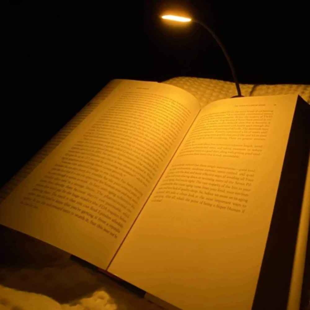 NoBlue leselampe festet på en åpen bok med varmt ravlys uten blått lys