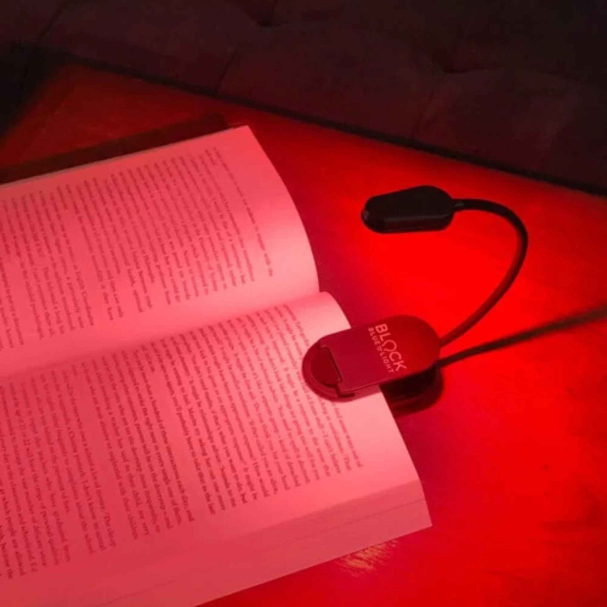 NoBlue leselampe festet på en åpen bok med rødt lys uten blått og grønt lys