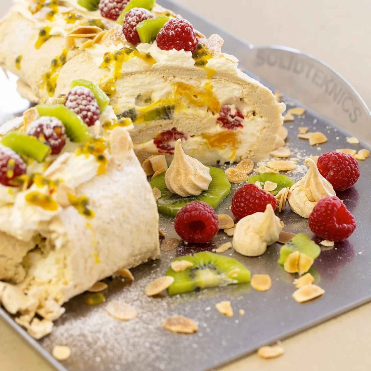 Pavlova med krem, bringebær, kiwi og pasjonsfrukt på nöni™ bakebrett i nikkelfritt rustfritt stål