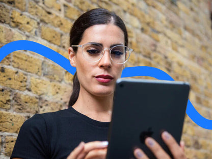 Kvinne med Ocushield Carson blålysbriller for dagtid ser på iPad. Klare glass beskytter mot skjermens blå lys og reduserer øyetretthet.