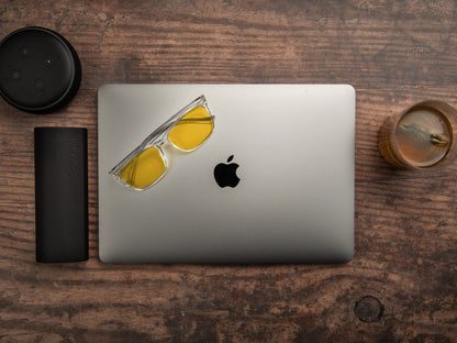 Ocushield Parker blålysbriller med klar innfatning og oransje glass for kveld, skjermbruk og bedre søvn, plassert på MacBook