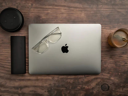 Parker klare blålysbriller med transparent innfatning liggende på MacBook ved siden av svart Ocushield etui