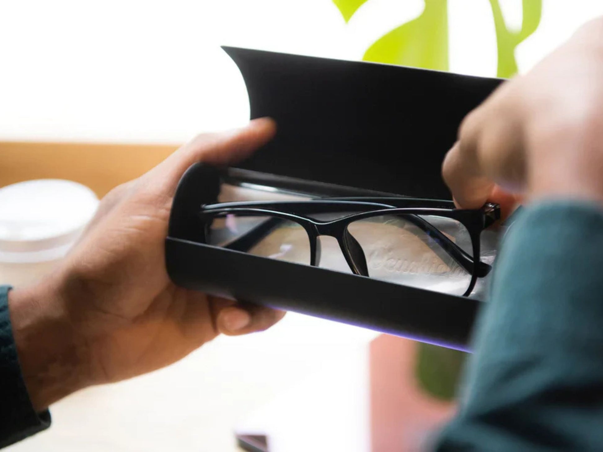 To herrehender som holder etuiet med svarte Parker Ocushield blålysbriller for dagbruk