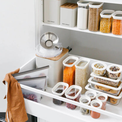 Ryddig pantry med plastfrie glassbeholdere og glasslokk brukt til oppbevaring av tørrvarer i kjøkkenskap